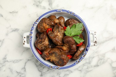 Photo of Bowl with delicious kidneys, pepper and parsley on white marble table, top view