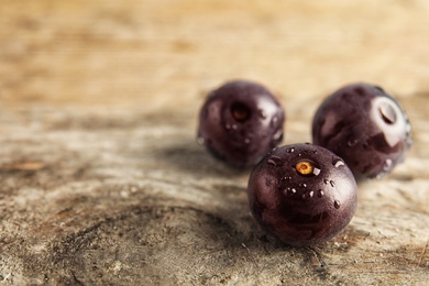 Photo of Fresh acai berries on wooden table, closeup