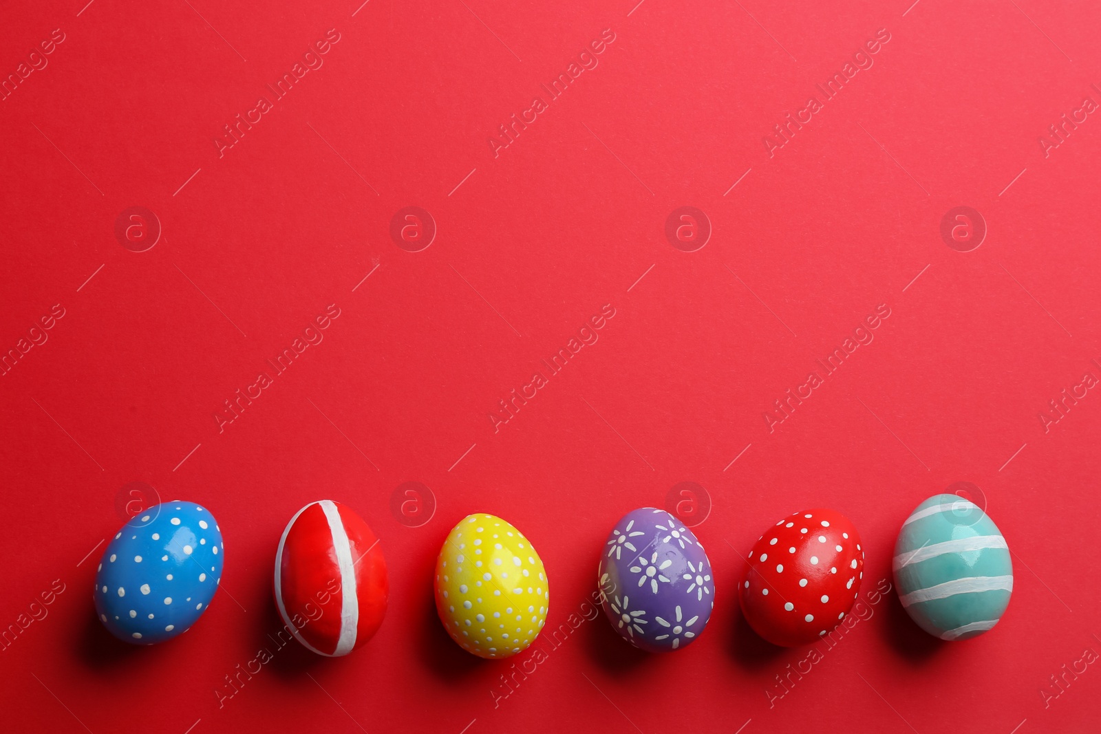 Photo of Flat lay composition of painted Easter eggs on color background, space for text