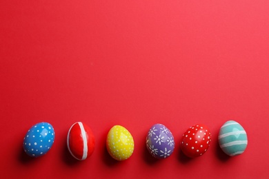 Photo of Flat lay composition of painted Easter eggs on color background, space for text