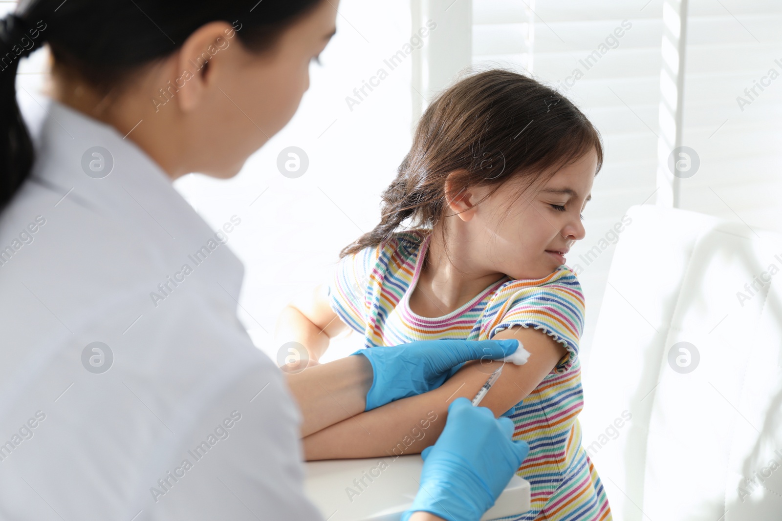 Photo of Doctor vaccinating little child in modern clinic