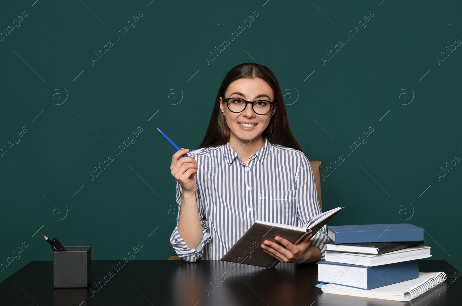 Photo of Portrait of young teacher at table against green background