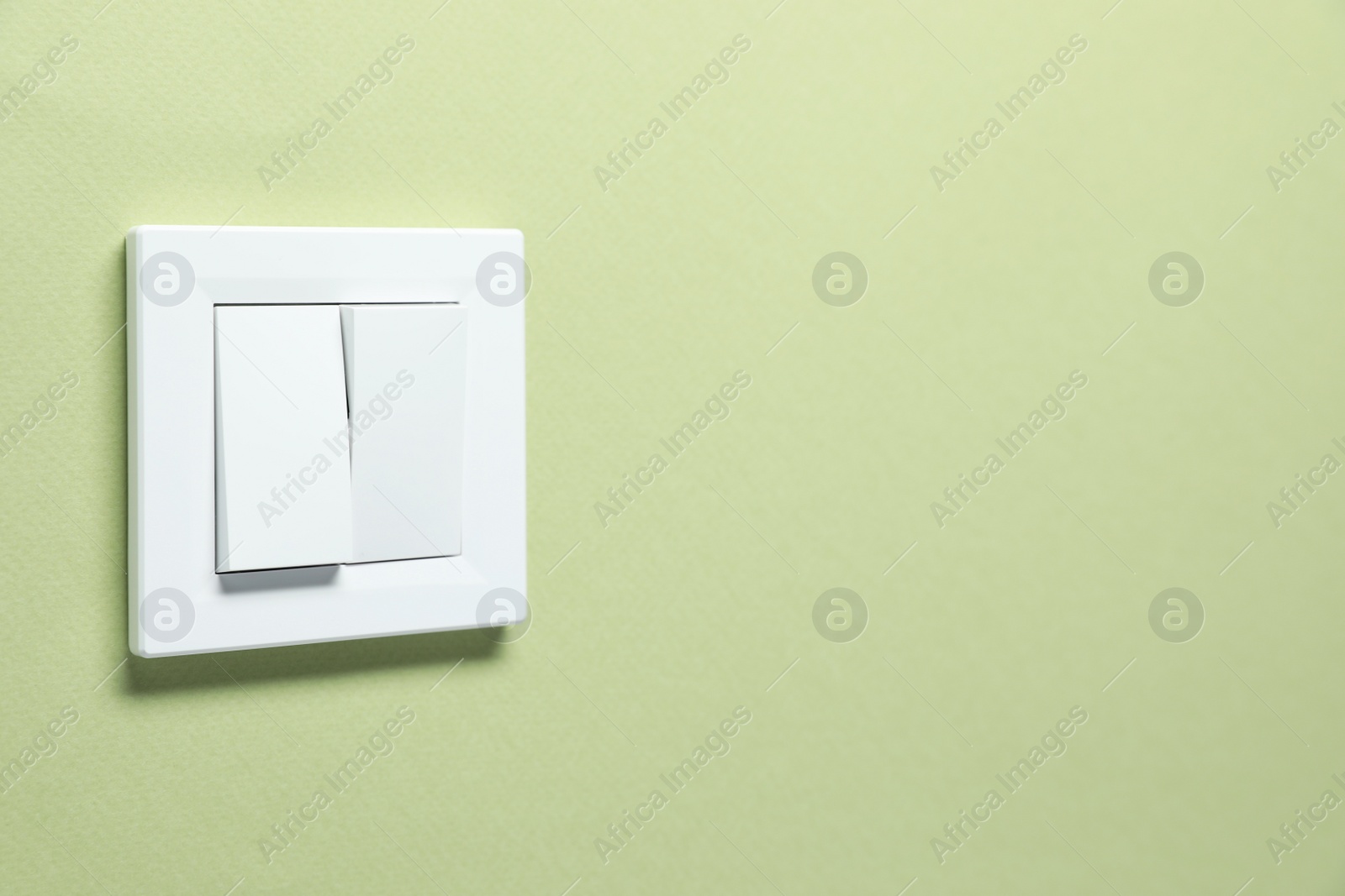 Photo of Modern plastic light switch on green background. Space for text