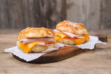 Photo of Delicious bagels with ham and cheese on wooden table. Space for text