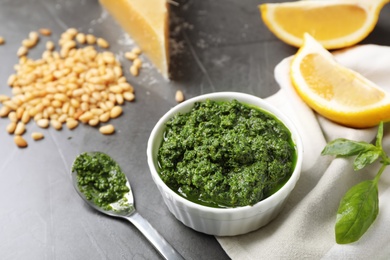 Photo of Bowl and spoon with basil pesto sauce on table