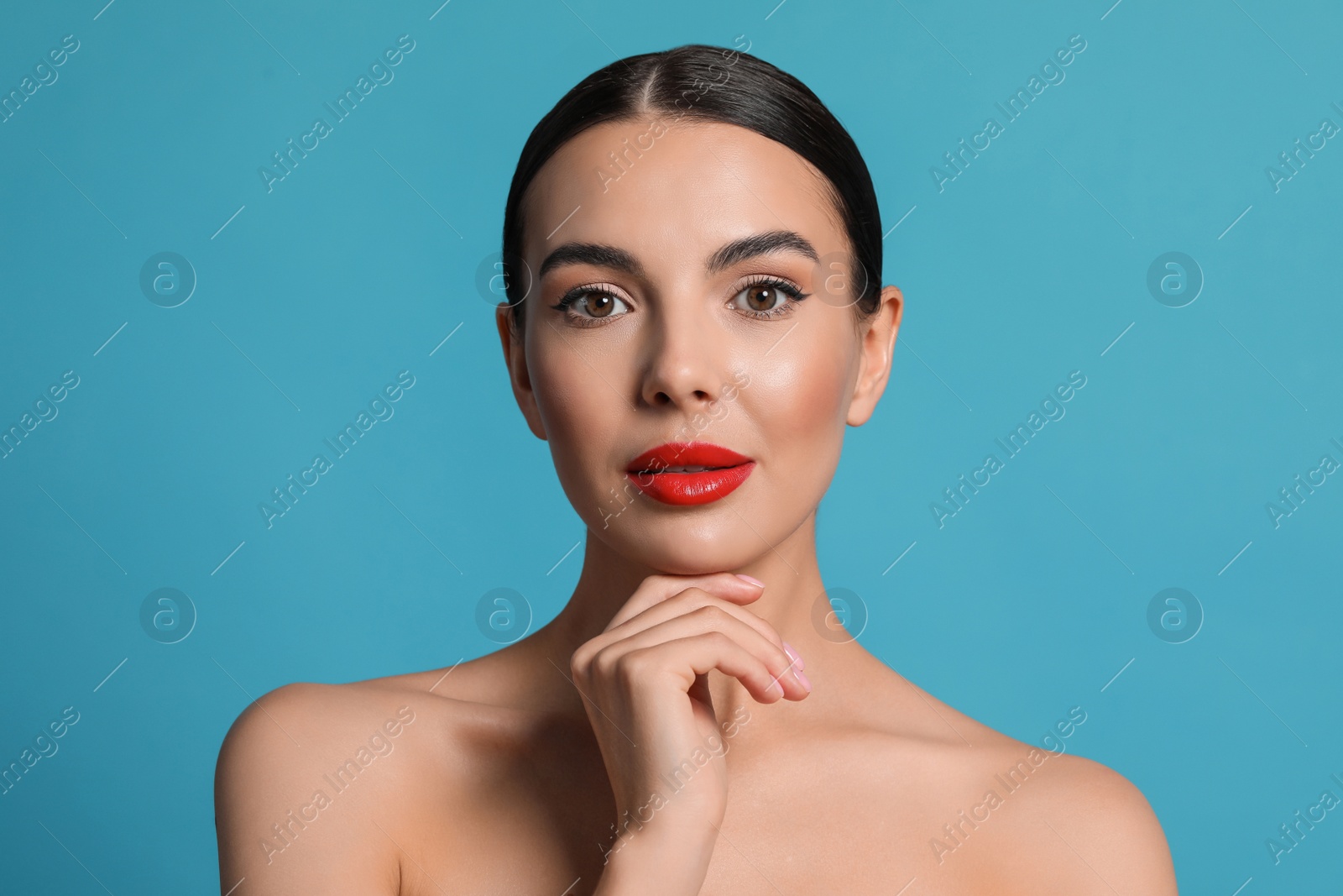 Photo of Attractive woman touching face against light blue background