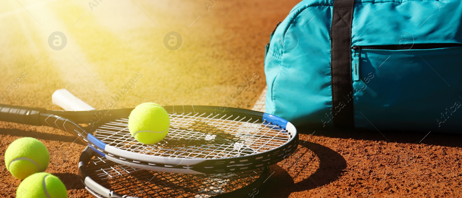 Image of Tennis balls, rackets and bag on clay court, banner design