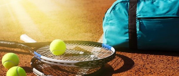 Image of Tennis balls, rackets and bag on clay court, banner design