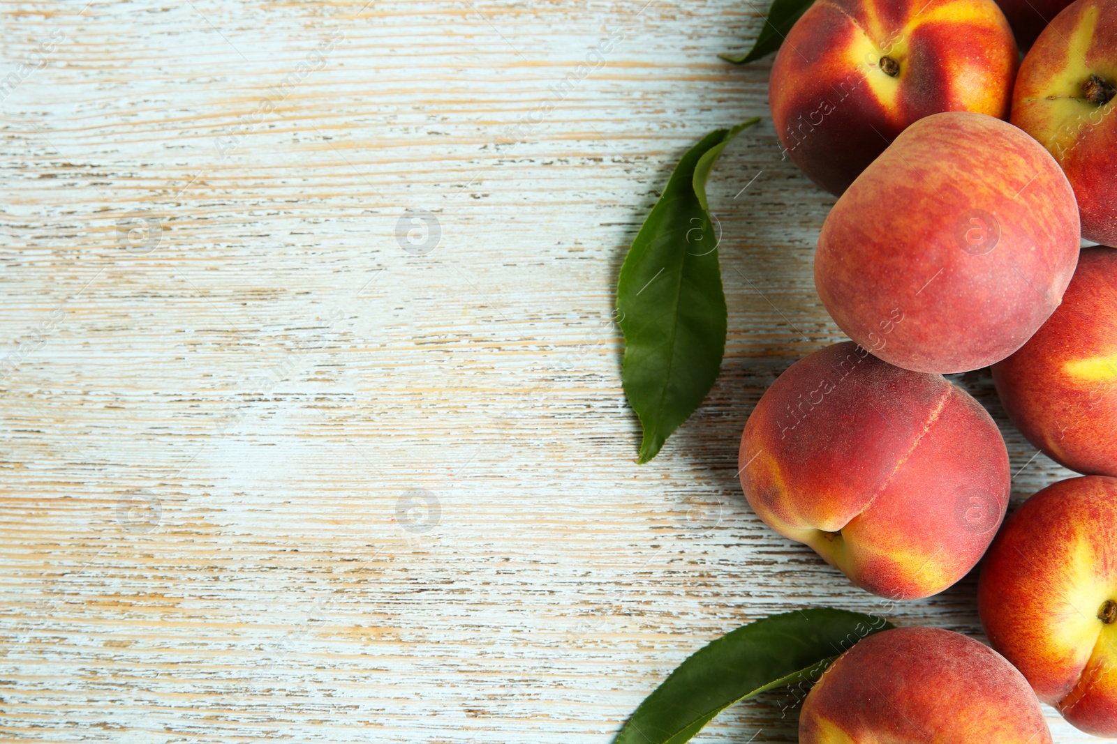 Photo of Fresh juicy peaches and leaves on blue wooden table, flat lay. Space for text