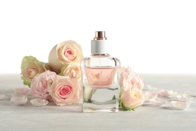Photo of Elegant bottle of perfume and flowers on light background