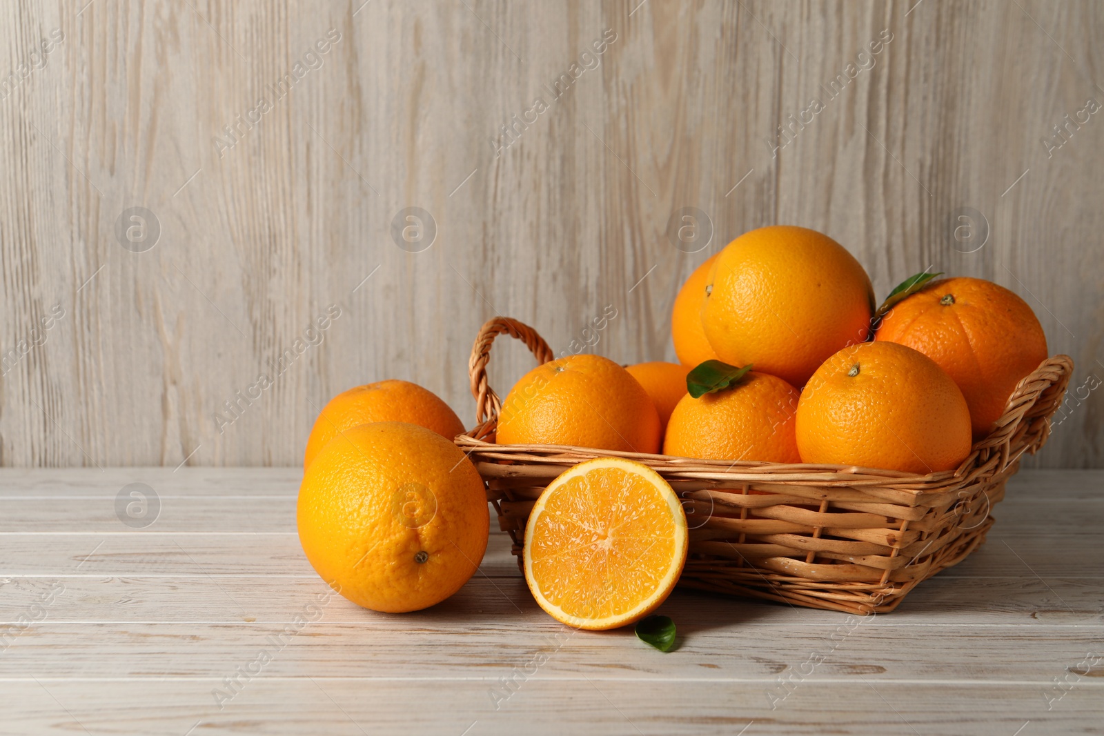 Photo of Many whole and cut oranges on light wooden table, space for text