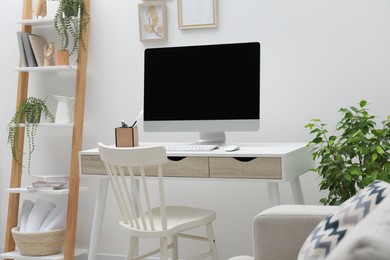 Photo of Spacious workspace with desk, chair, computer and potted plants at home