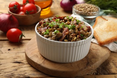 Photo of Delicious lentils with bacon and green onion in bowl served on wooden table, closeup