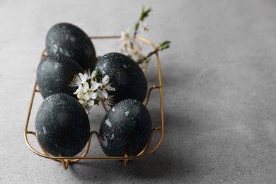 Decorated Easter eggs and flowers on grey table, closeup. Space for text
