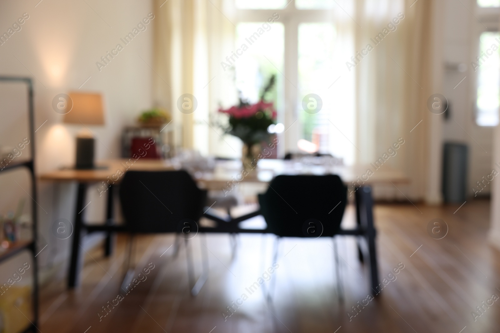 Photo of Stylish dining room with comfortable furniture, big window and bouquet of flowers, blurred view