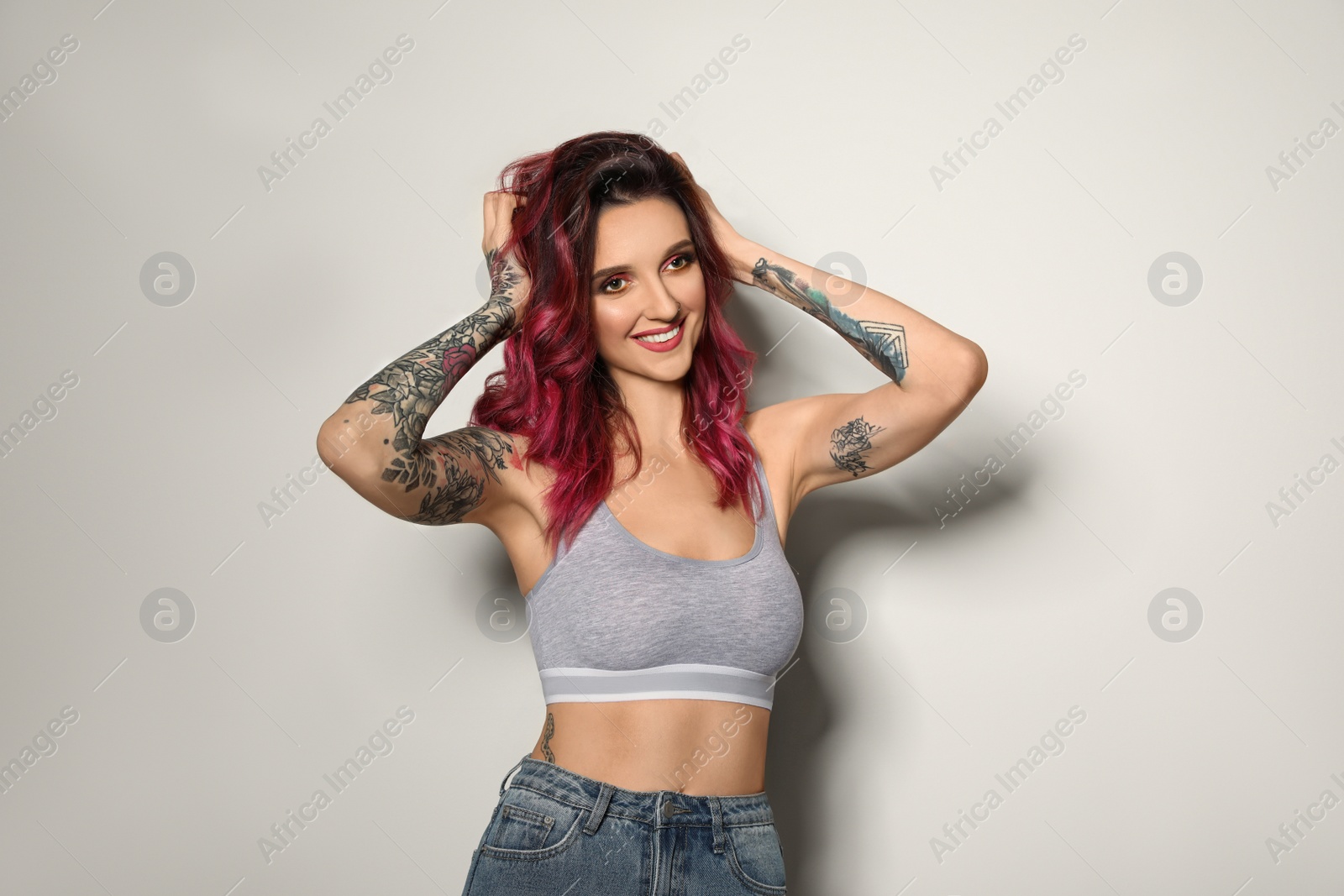 Photo of Beautiful woman with tattoos on body against light background