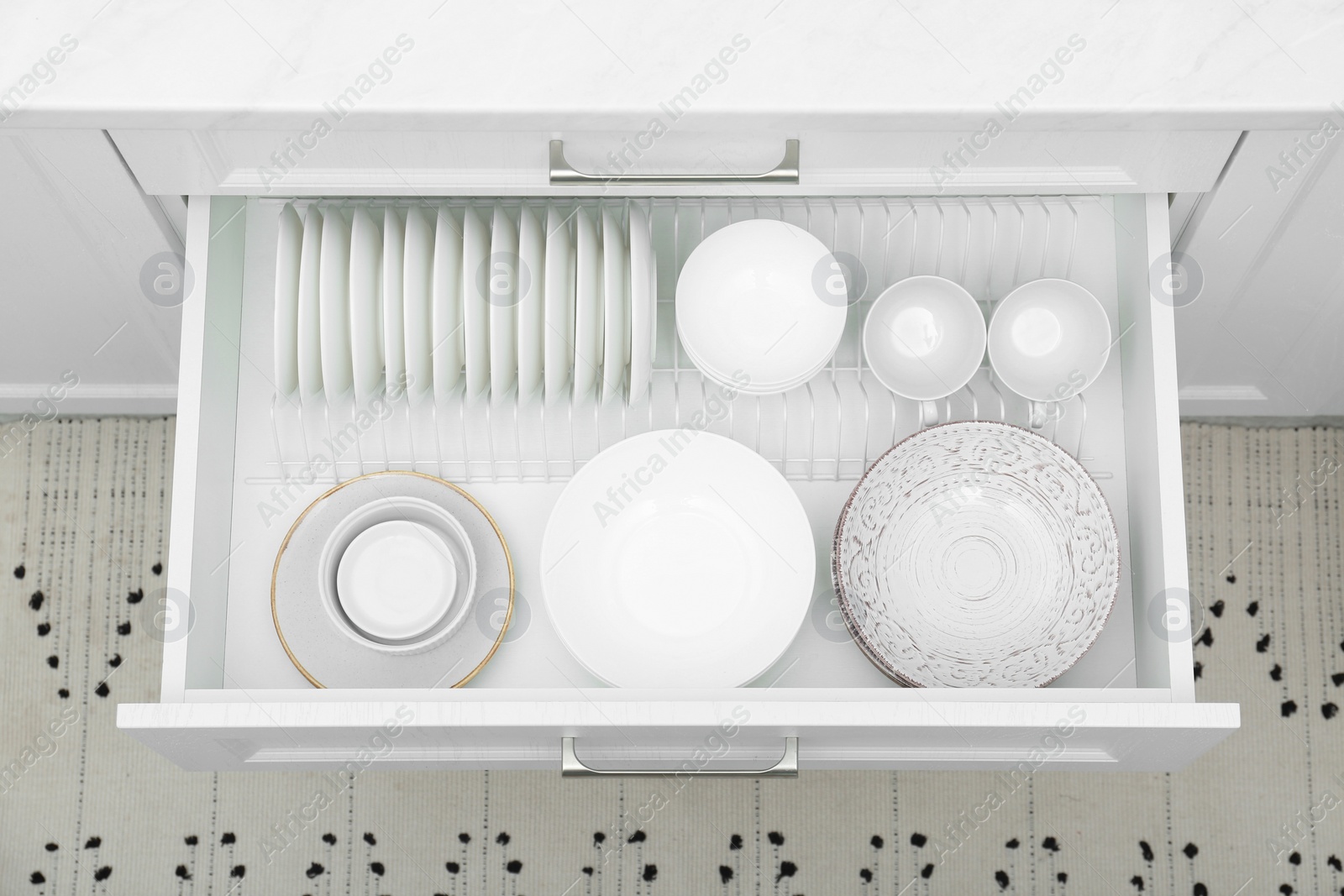 Photo of Open drawer with different plates and bowls in kitchen, above view