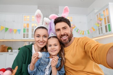 Happy family making selfie while painting Easter eggs in kitchen