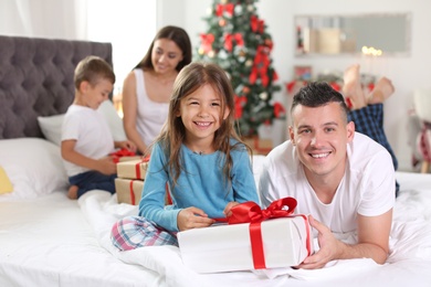 Photo of Happy parents and children exchanging gifts on Christmas morning at home