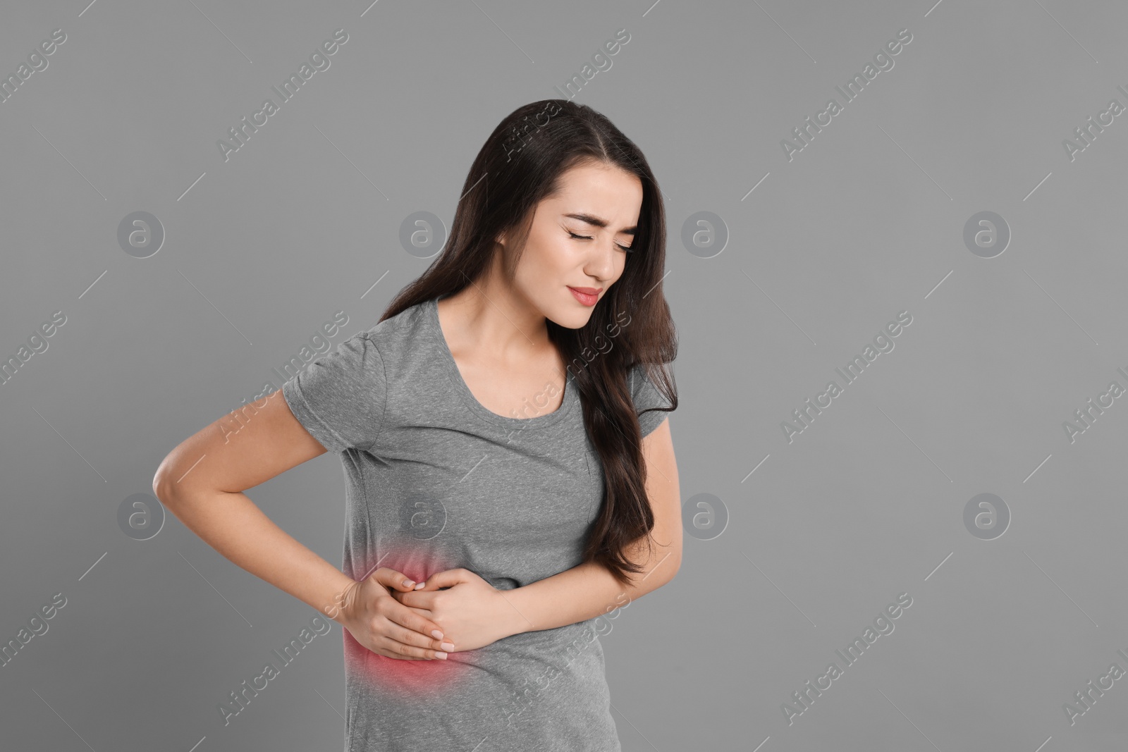 Photo of Young woman suffering from liver pain on grey background