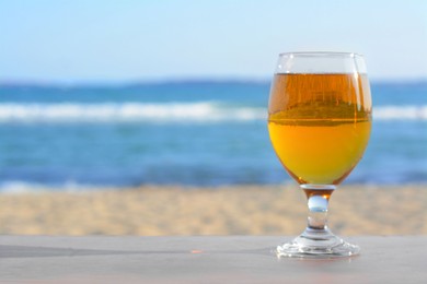 Photo of Glass of cold beer on wooden table at beach. Space for text