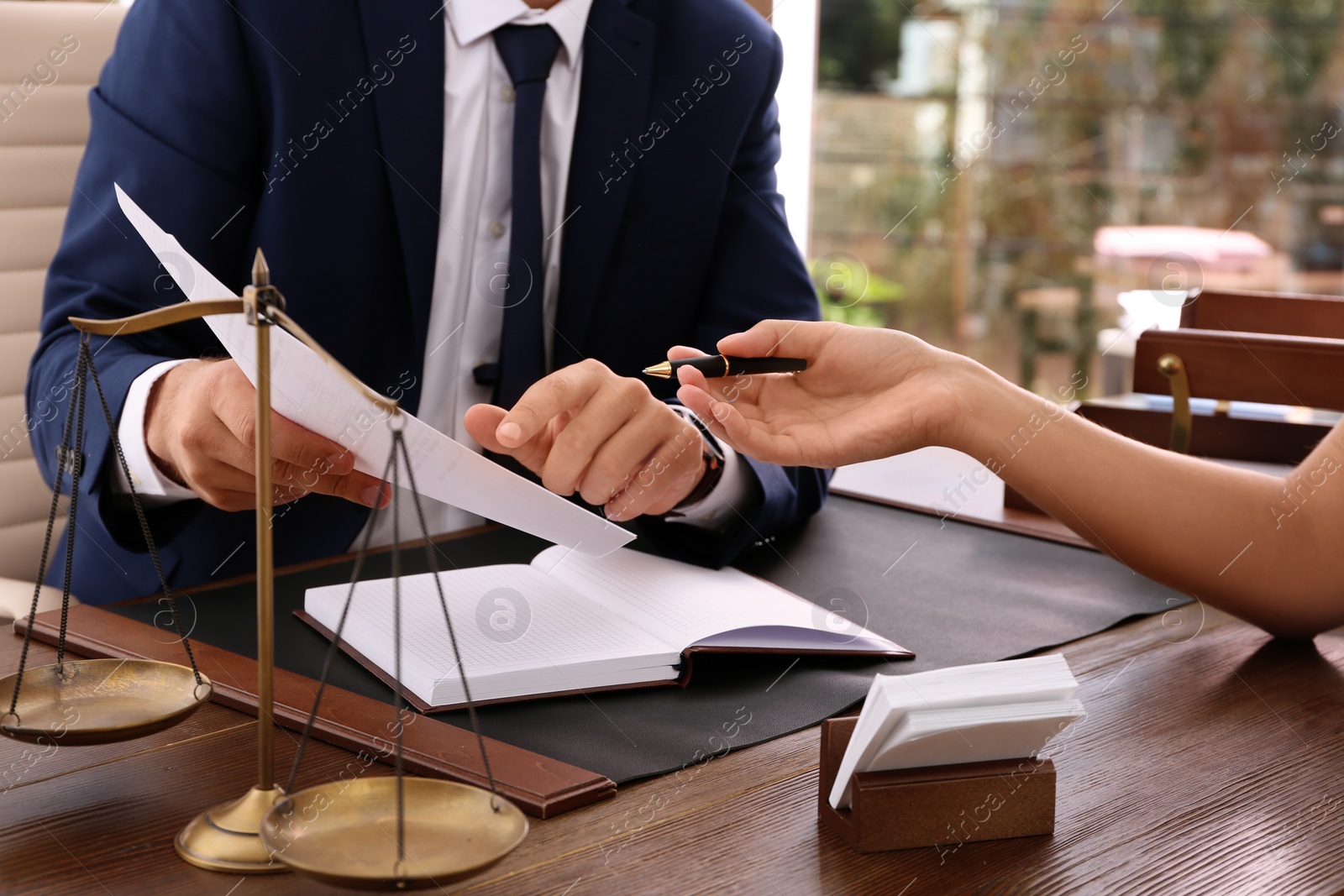 Photo of Lawyer working with client at table in office, focus on hands