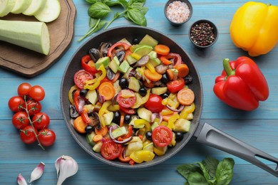Photo of Mix of tasty vegetables in pan and ingredients on light blue wooden table, flat lay