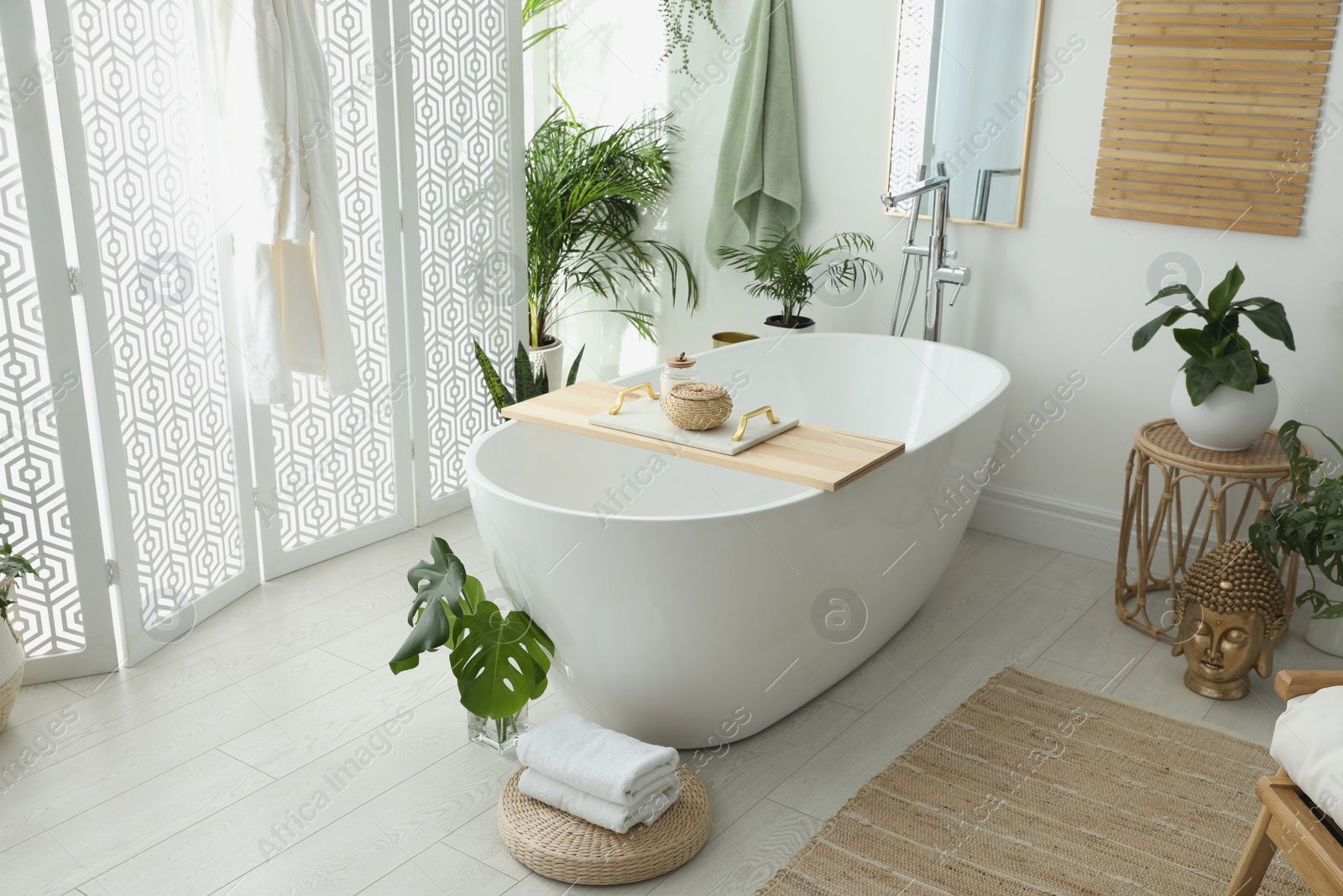 Photo of Stylish bathroom interior with modern tub, houseplants and beautiful decor. Home design