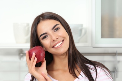 Photo of Happy woman holding fresh apple in kitchen