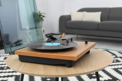 Photo of Vinyl record player on wooden table indoors. Interior element