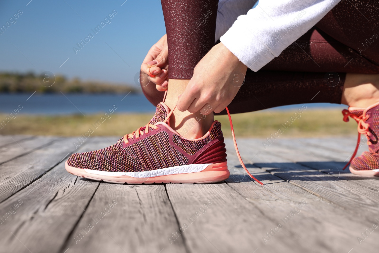 Image of Sporty woman tying shoelaces outdoors on sunny morning, closeup