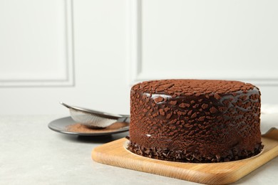 Photo of Delicious chocolate truffle cake and cocoa powder on light grey table