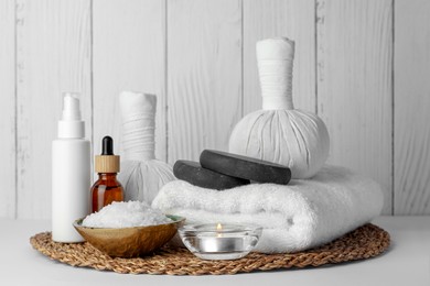 Composition with different spa products and candle on white table against wooden background