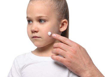 Photo of Father applying ointment onto his daughter's cheek on white background