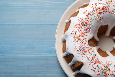 Photo of Glazed Easter cake with sprinkles on blue wooden table, top view. Space for text