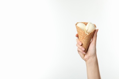 Woman holding delicious ice cream in waffle cone on white background, closeup