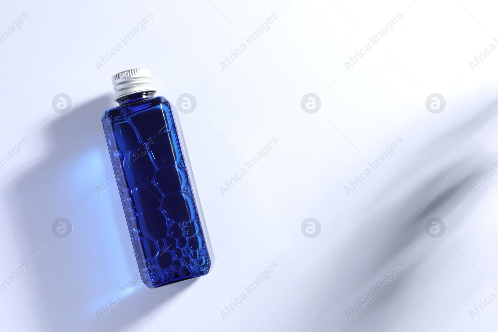 Photo of Bottle of cosmetic product on white background, top view. Space for text