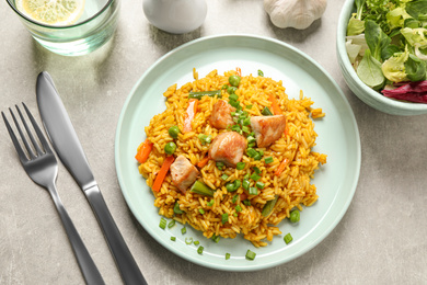 Photo of Delicious rice pilaf with vegetables and chicken served on light grey table, flat lay