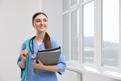 Photo of Smart medical student with folders in college hallway, space for text