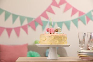 Delicious cake decorated with macarons and marshmallows and clean tableware on wooden table in festive room, space for text