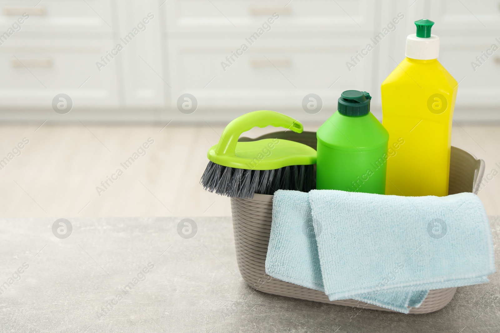 Photo of Different cleaning supplies in basket on table. Space for text