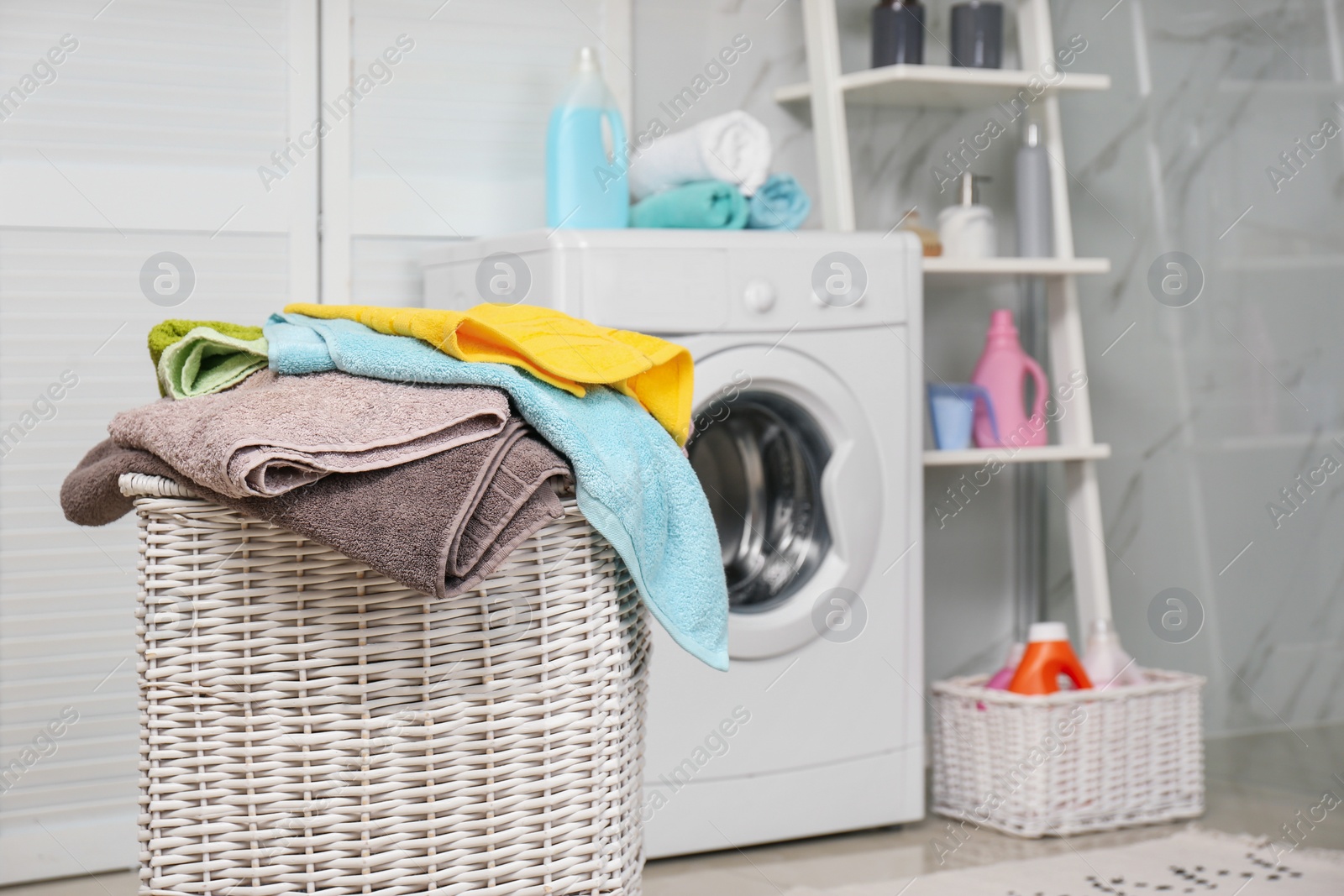 Photo of Wicker basket with laundry and washing machine in bathroom. Space for text