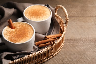 Delicious eggnog with cinnamon on wooden table. Space for text