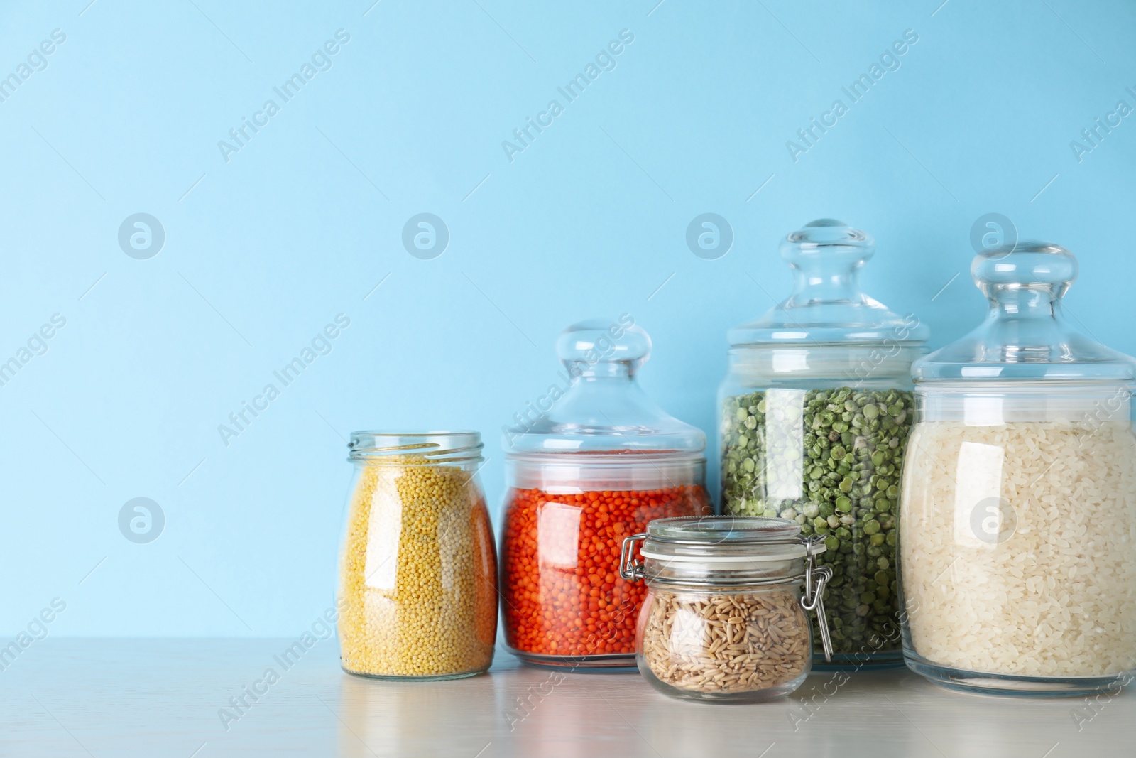 Photo of Glass jars with different types of groats on white wooden table