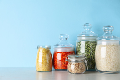 Photo of Glass jars with different types of groats on white wooden table