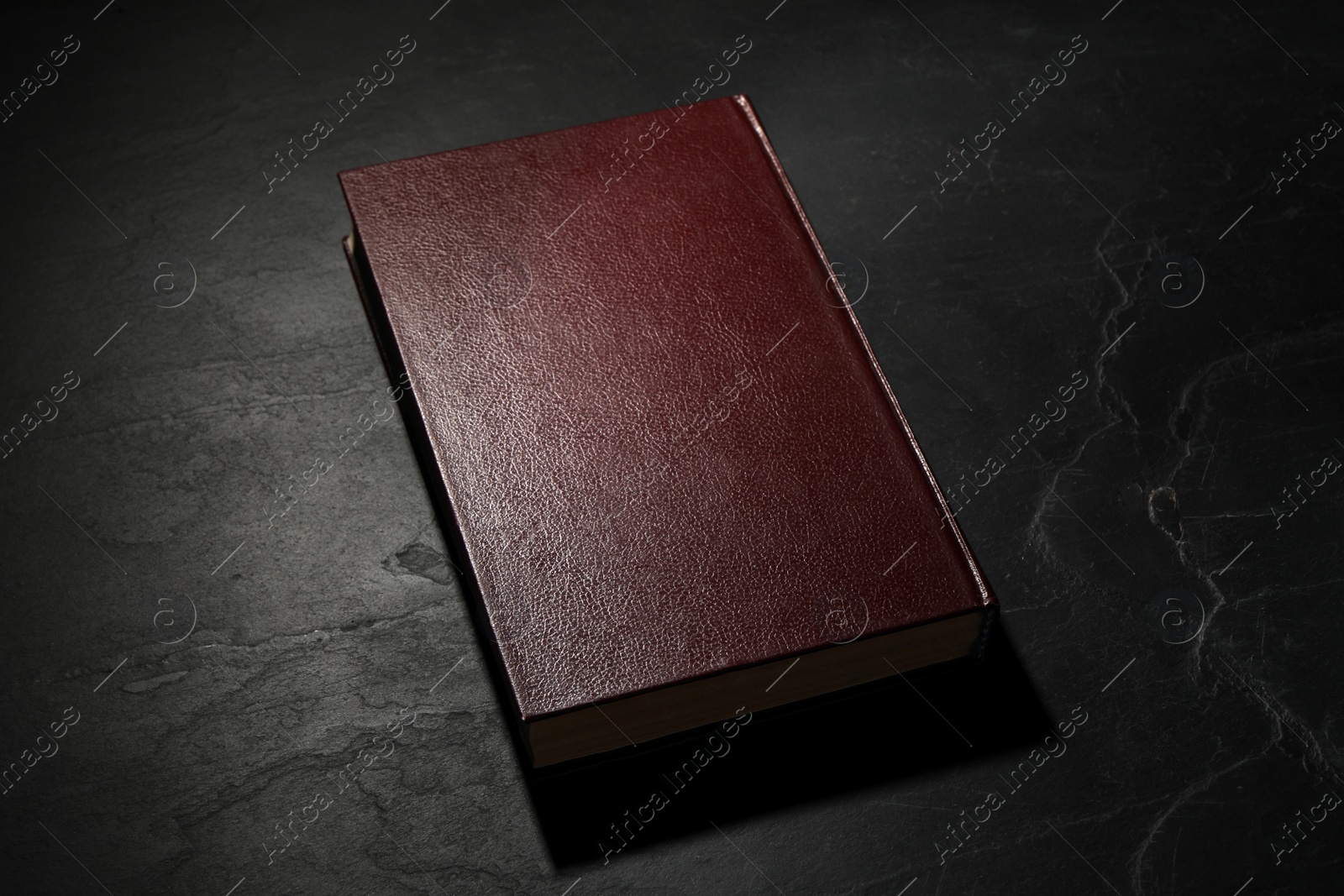 Photo of One old hardcover book on black textured table