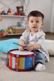 Photo of Cute little boy playing toy drum at home
