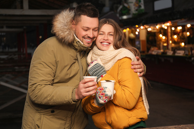 Happy couple with mulled wine at winter fair