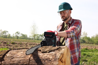 Man sawing wooden log on sunny day