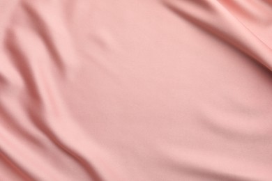 Photo of Crumpled pink silk fabric as background, top view. Space for text